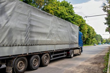 Arkasını muşambayla örten büyük bir tır yolda ilerliyor..