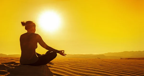 Woman sitting in lotus position on sand dune at sunset — Stock Photo, Image