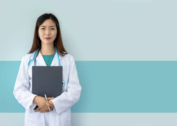 アジアの女性医師を笑顔で研究室のコートと聴診器とフォルダをライトブルーの背景に — ストック写真