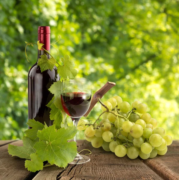 Vino tinto, hojas de vid y uva sobre mesa de madera — Foto de Stock