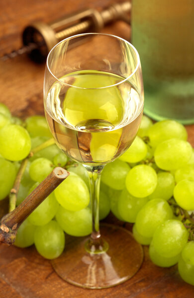 Бокал белого вина и виноград на деревянном столе
