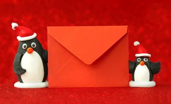 Small penguins holding a red paper envelope — Stock Photo, Image