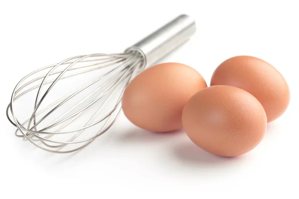Three eggs and whisk isolated on white background — Stock Photo, Image