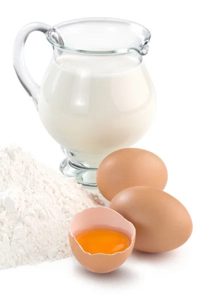 Huevos, jarra de leche y harina sobre fondo blanco — Foto de Stock