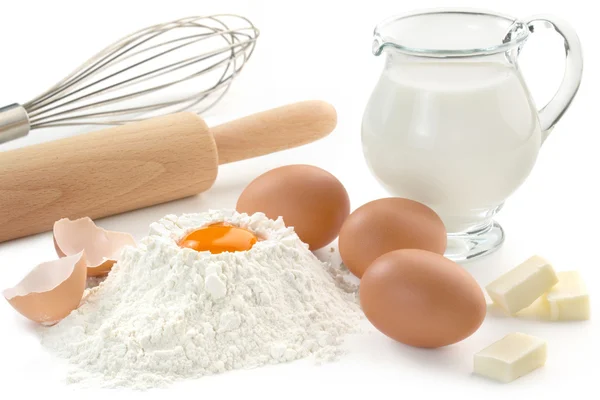 Яйца, мука, молоко, масло и кухонная утварь — стоковое фото