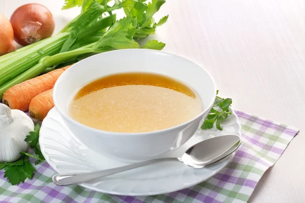 Kom van Bouillon en verse groenten op houten tafel — Stockfoto