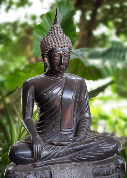 Staty av Buddha i en bakgrund av gröna blad — Stockfoto