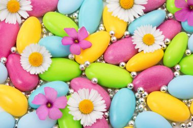 Heap of colored sugar coated almonds and wildflowers clipart