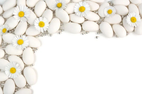 White dragees with silver spheres and daisies on white background