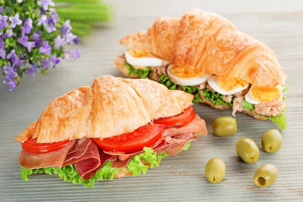 Croissant sandwiches and green olives on wooden table — Stock Photo, Image