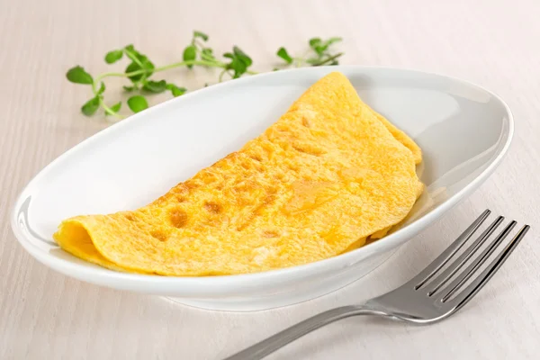 Omelet plaat en vork op houten tafel — Stockfoto