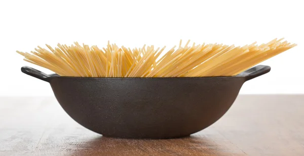 Сырые спагетти в железной кастрюле изолированы — стоковое фото