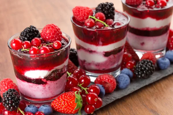 Nahaufnahme von geschichtetem Dessert mit roten Früchten auf Holzgrund — Stockfoto