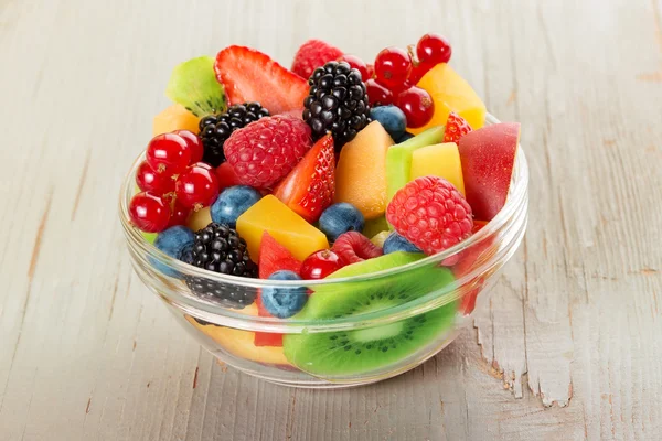 Bowl of fruit salad isolated on wood table — ストック写真