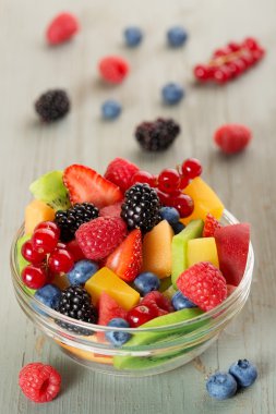 Bir cam kase ve ahşap masa üzerinde çilek meyve salatası