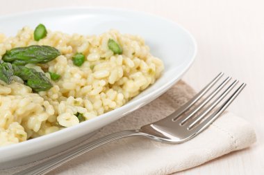 Kuşkonmaz ve bej peçete üzerinde çatalı ile risotto yemek