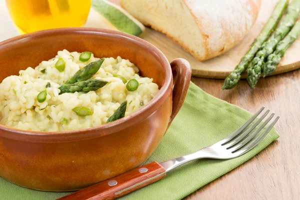 Risoto com espargos em uma tigela de terracota sobre um guardanapo verde — Fotografia de Stock