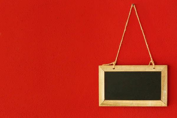 Blank chalkboard hanging on the red wall — Stock Photo, Image