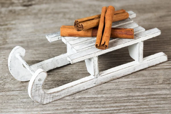 Cinnamon sticks over a white wooden sleigh — Stock Photo, Image