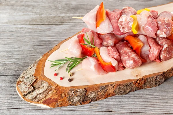 Brochettes and peppercorn on a rustic chopping board — Stock Photo, Image
