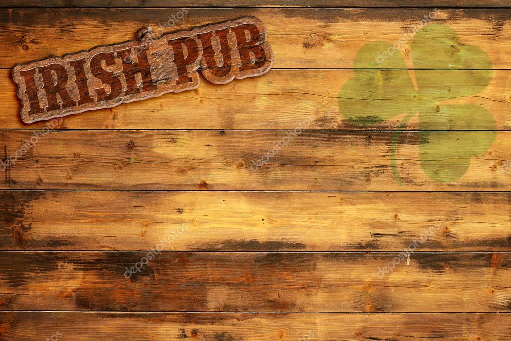 Irish pub label and green shamrock on wooden background