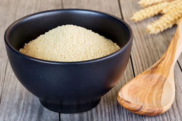 Couscous in een zwarte kom en houten lepel — Stockfoto