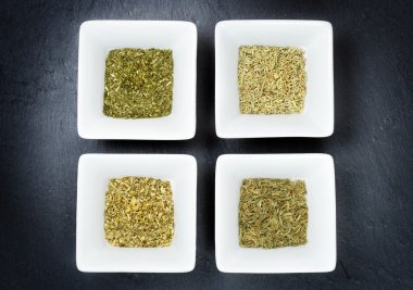 slate üzerinde kurumuş otlar ile dört kase