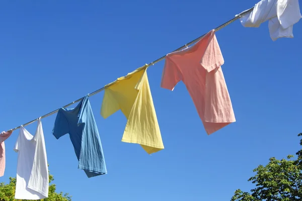 Camisetas colgando de una cuerda delante del cielo azul — Foto de Stock