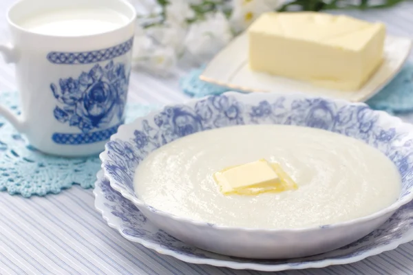 Grießbrei mit frischer Butter und einem Becher Milch — Stockfoto