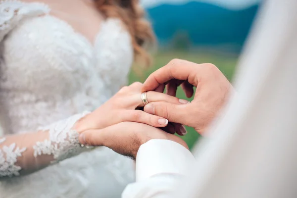 Mans hand putting a wedding ring on the brides — Stock Photo, Image