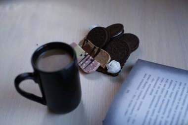 Kahvaltı masanın üstünde. Kurabiyeli kahve, çikolata ve bir kitap. Yüksek kalite fotoğraf