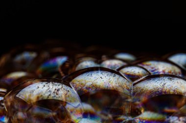 Kabarcıklı soyut doku. Siyah arka planda gökkuşağı sabun köpüğü. Renkli bir yüzeye yakın çekim.