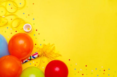 Sarı masa manzaralı renkli balonlar ve konfetiler. Şenlik ya da parti geçmişi. Düz yatış stili. Doğum günü tebrik kartı. Karnaval.