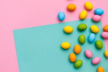 Paskalya tavşanı. Mutlu Paskalya tatili arka plan kavramı. Düz, ofis masasındaki modern kırsal pembe pastel kağıtta kutlama için aksesuarlı renkli tavşan yumurtası yatıyordu..