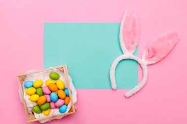 Paskalya tavşanı. Mutlu Paskalya tatili arka plan kavramı. Düz, ofis masasındaki modern kırsal pembe pastel kağıtta kutlama için aksesuarlı renkli tavşan yumurtası yatıyordu..