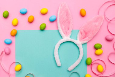 Paskalya tavşanı. Mutlu Paskalya tatili arka plan kavramı. Düz, ofis masasındaki modern kırsal pembe pastel kağıtta kutlama için aksesuarlı renkli tavşan yumurtası yatıyordu..