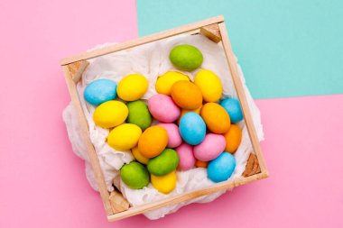 Paskalya tavşanı. Mutlu Paskalya tatili arka plan kavramı. Düz, ofis masasındaki modern kırsal pembe pastel kağıtta kutlama için aksesuarlı renkli tavşan yumurtası yatıyordu..