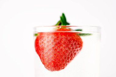 Beyaz arka planda, safra suyunda çilek. Kokteyl reklamı. Suyun altında sulu meyveler. Suya batarken vurulmuşlar. Ürün tanıtımının sağlıklı bir şekli.