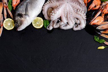 Siyah arka planda sağlıklı balık ve deniz ürünleri çeşitleri. Üst Manzara. Siyah kırsal arka planda deniz ürünleri. 