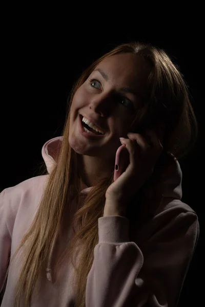 Cep telefonuyla konuşan genç bir kadının sade portresi. Yüzünde mutlu bir gülümseme. — Stok fotoğraf