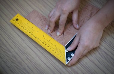 Ahşap köşelerin tahta üzerinde kare olup olmadığını kontrol etmek için bir deneme karesi kullanan kadın eller. 