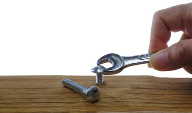 Bir İngiliz anahtarıyla, beyaz arka planda tahta bir tahtaya vidalayan bir İngiliz 'in yakın plan çekimi başarısız bir kavram olarak araçların yanlış bir çaba