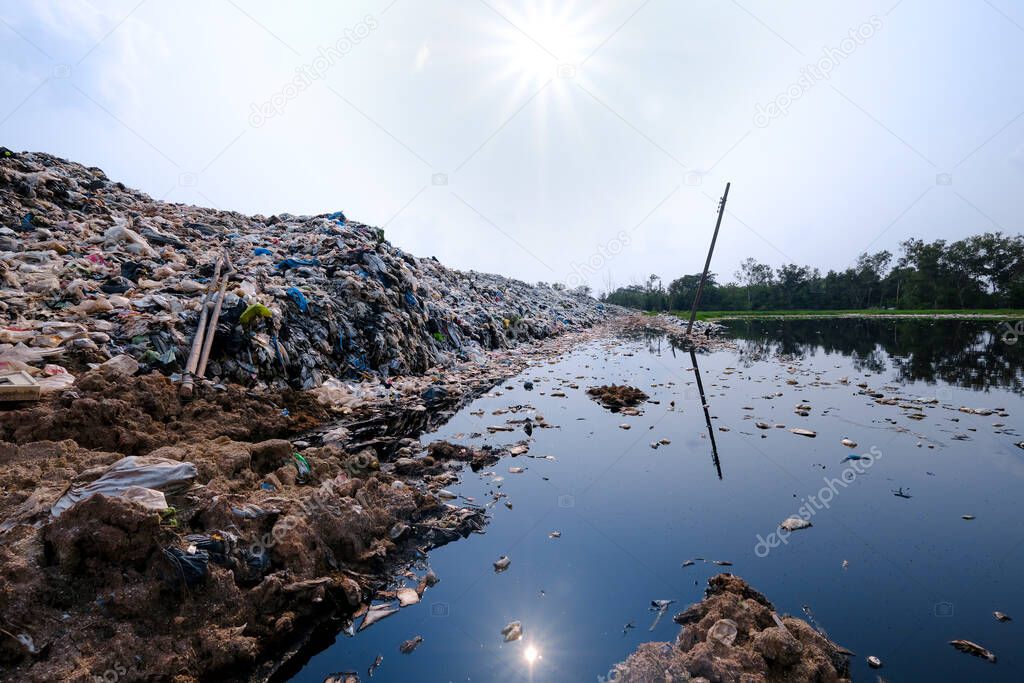 Polluted water and mountain large garbage pile and pollution at the sun the background, Pile of stink and toxic residue