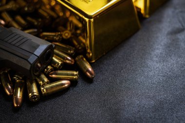 Kurşunlu siyah tabanca ve altın külçeli arka plan.