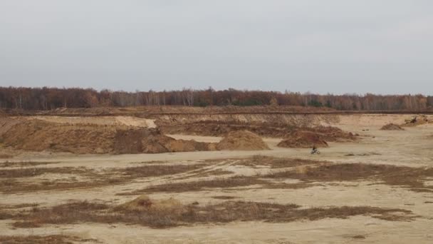 Mann auf Rennmotorrad fährt auf sandigem Gelände und springt über kleinen Hügel. — Stockvideo