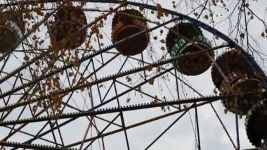 Bulutlu bir sonbahar günü. Kara bulutlu gökyüzü. Alt manzara. Eğlence parkında gri gümüş metalde dönme dolap. Dönme dolap yavaşça daire çiziyor..