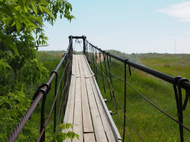 Nehir üzerindeki ahşap köprü ve gökyüzüne uzanan çayır.