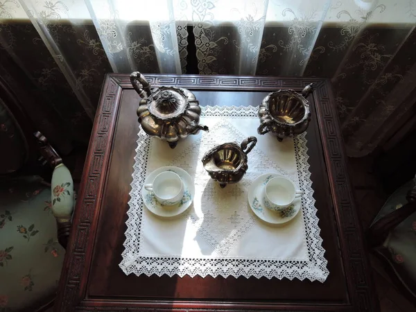 old ceramic tableware and coffee grinder on the table in antique kitchen room.