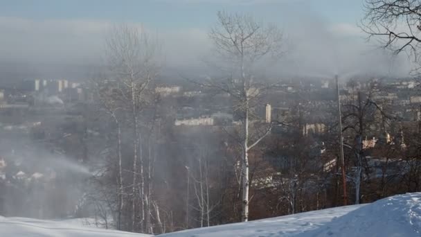 Cañón de nieve preparando una pendiente para esquiar en el fondo del paisaje urbano — Vídeos de Stock