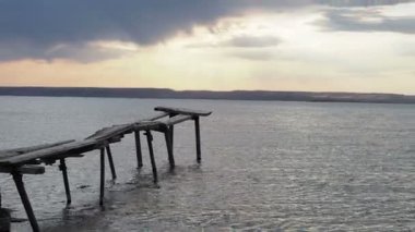 Gün batımında nehrin üzerindeki eski ahşap köprü. Arka planda dağlar ve tepeler